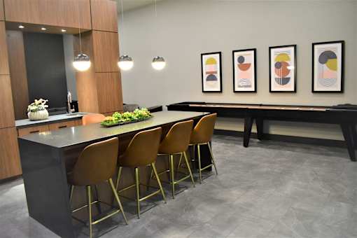 A modern kitchen with a bar area and chairs.