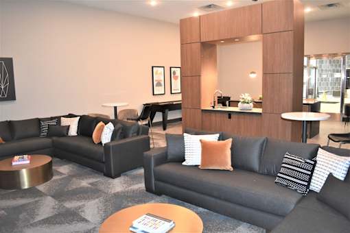 A living room with black couches and a wooden mirror.