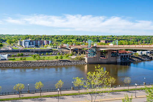 A bridge over a river with trees and buildings in the background.