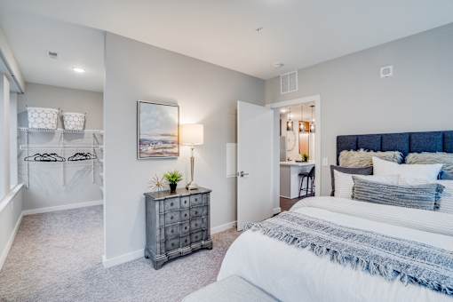 A bedroom with a large bed and a dresser with a plant on top.