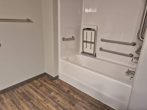 A white bathtub with a shower head and hand held shower.