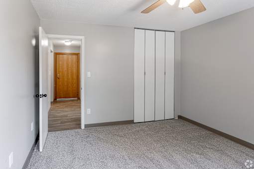 A room with a brown door and a ceiling fan.