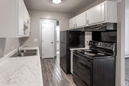 A black stove in a kitchen with white cabinets.
