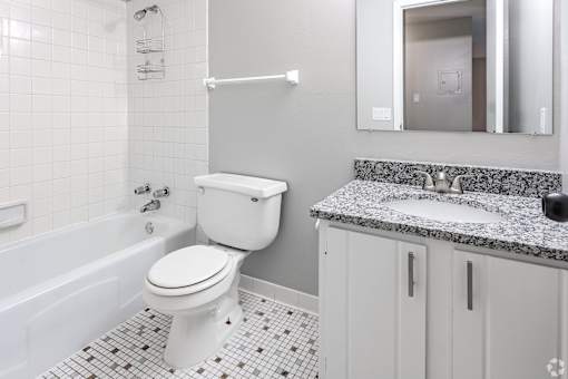 A white toilet sits in a bathroom next to a bathtub.