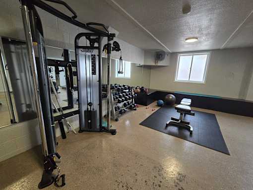A gym with a variety of equipment including a squat rack, a bench, and a ball.