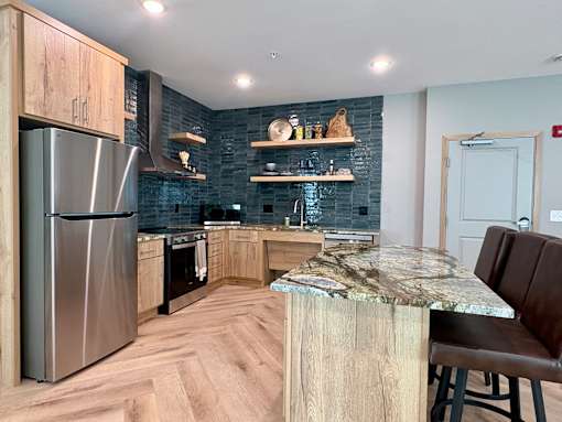 A modern kitchen with a marble countertop and wooden cabinets.