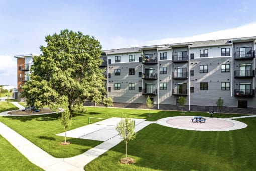 an exterior view of Golden Aspen Flats with a pickle ball court, picnic area, grass and trees