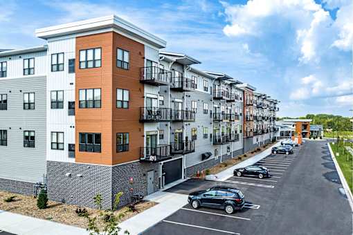 A row of modern apartment buildings with cars parked in the driveway.