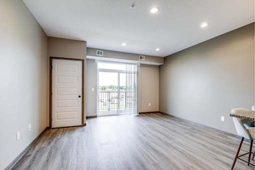A room with a wooden floor and a sliding glass door leading to a balcony.