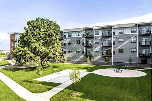 Apartment complex with a green lawn and a playground.