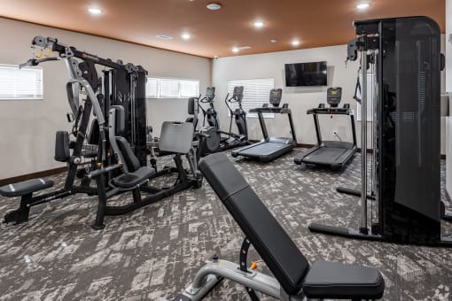 a gym with cardio equipment and a tv in the ceiling