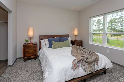 A bedroom with a large bed and two lamps.