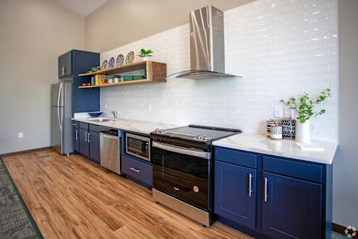 A kitchen with blue cabinets and a white backsplash.