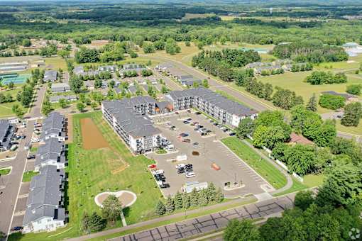 A bird's eye view of a large building complex surrounded by trees and a parking lot.