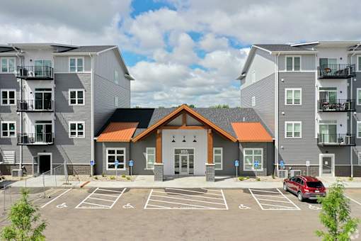A modern apartment complex with a central building and parking lot.