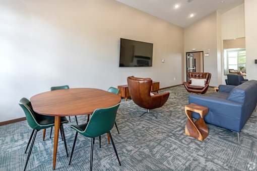 A living room with a round wooden table surrounded by chairs.