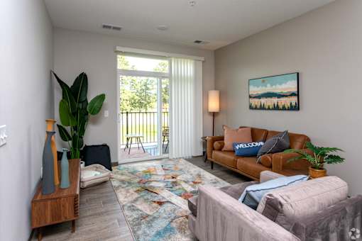 A living room with a couch, a chair, a rug, and a painting on the wall.