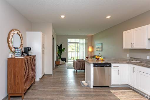 A kitchen with white cabinets and a wooden floor.