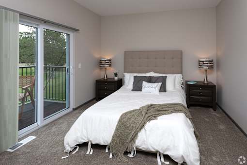 A bedroom with a large bed and a sliding glass door.