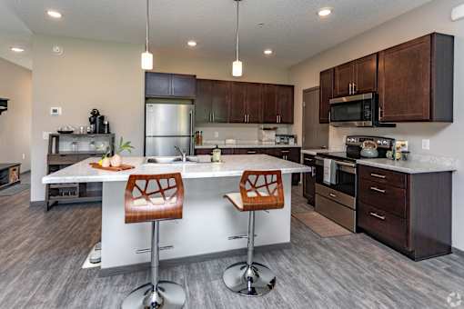 A modern kitchen with a white island and wooden chairs.
