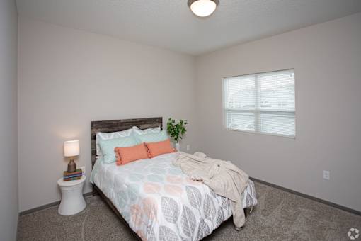 A bedroom with a bed, nightstand, and window.