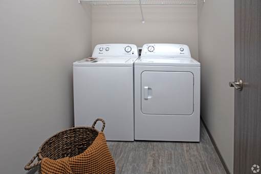 Two white front loading washing machines in a laundry room.