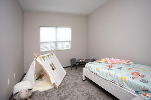 A child's bedroom with a teepee tent and a bed with a colorful blanket.
