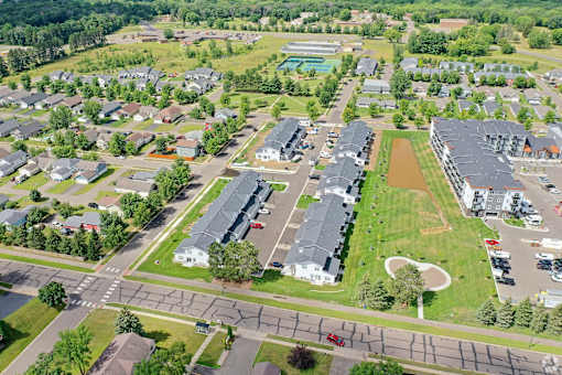 A bird's eye view of a residential area with houses, roads, and a park.
