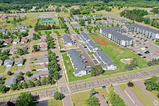 A bird's eye view of a residential area with apartment buildings, houses, and a swimming pool.
