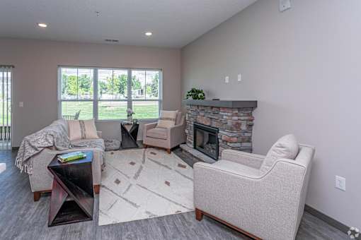 A living room with a stone fireplace and a large window.