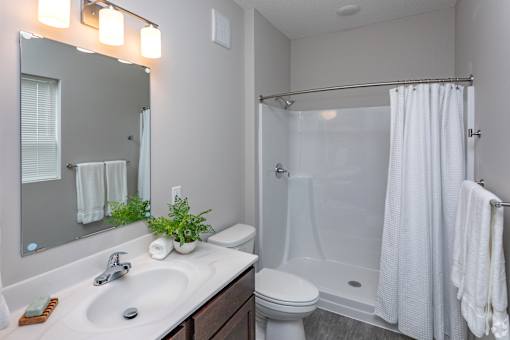 A white bathroom with a sink, toilet, and shower.