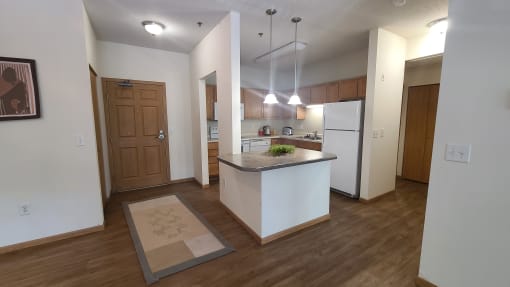 a kitchen and living room with white walls and wood flooring