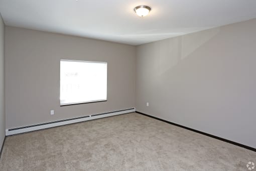 an empty room with a window and carpet