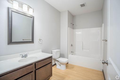 A white bathroom with a toilet, sink, and mirror.