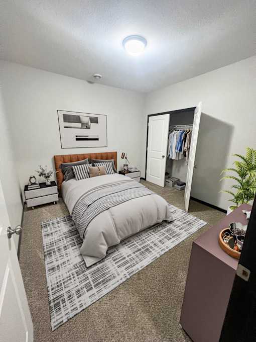 A bedroom with a bed, a dresser, and a plant.