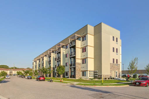 A large apartment building with cars parked in front.