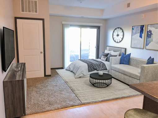 A living room with a grey couch and a large window.