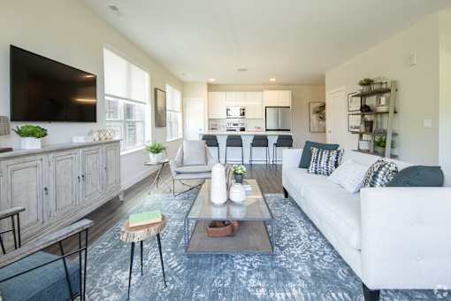 A modern living room with a white couch, a wooden coffee table, and a flat-screen TV mounted on the wall.