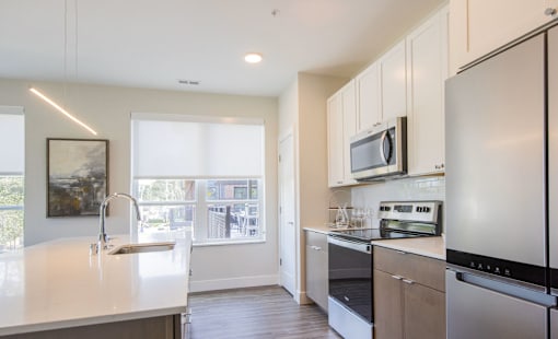 A modern kitchen with stainless steel appliances and a large window.