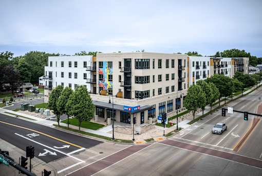 A street view of a city intersection with a white building on the corner at Bloom, Monona, WI, 53716