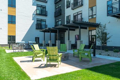 A patio with green chairs and a table in front of a building at Bloom, Monona, WI