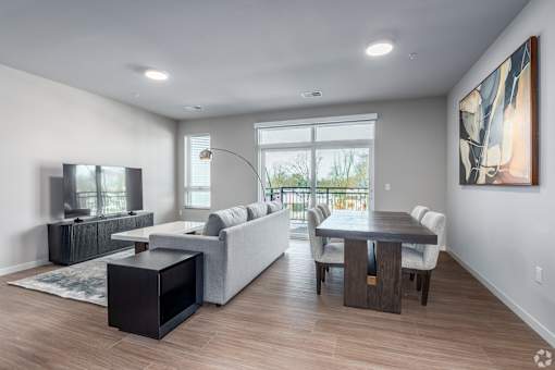 A modern living room with a grey couch, a black coffee table, and a large painting on the wall at Bloom, Monona