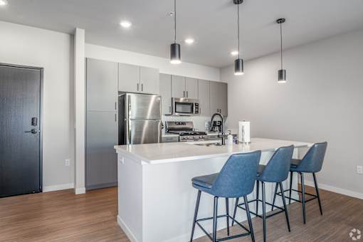 A modern kitchen with a white island and blue chairs at Bloom, Monona, Wisconsin