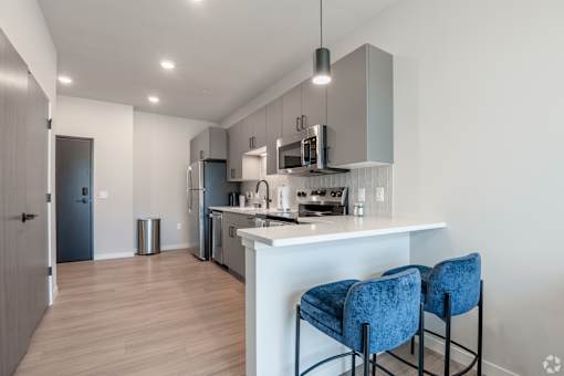 A kitchen with a white counter and blue chairs at Bloom, Monona, 53716