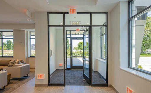 A hallway with exit signs on the wall and doors.