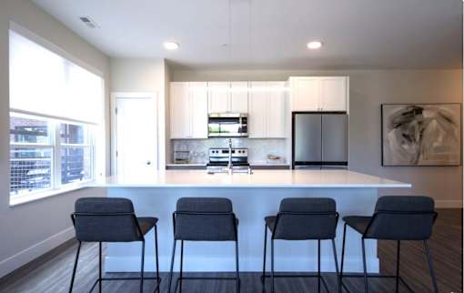 A modern kitchen with a bar area and chairs.