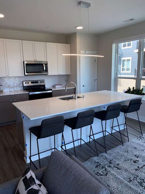 A kitchen with a white island and black barstools.
