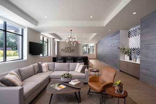 A modern living room with a grey sofa, a wooden coffee table, and a large window.