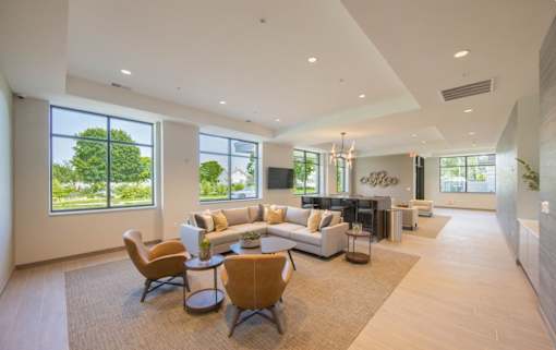 A spacious living room with a large window, a couch, a chair, and a coffee table.