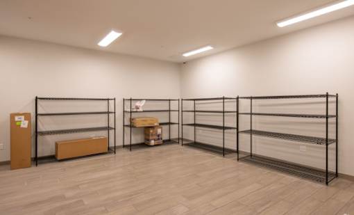 A room with a white wall and a wooden floor with a shelf and a box on it.